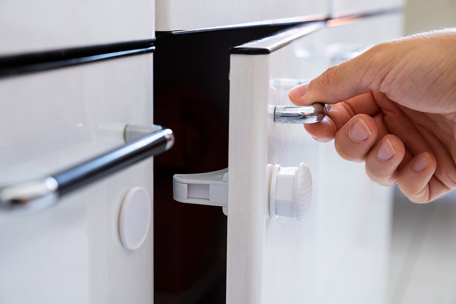 Close up of a white cabinet with a baby-proof lock system.